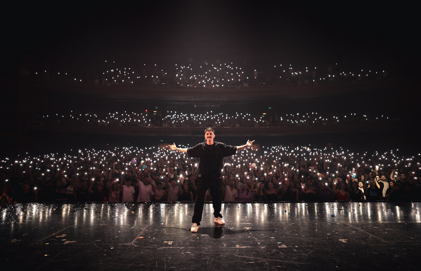 Juli Bellese con los brazos abiertos frente a una sala llena en el Gran Rex